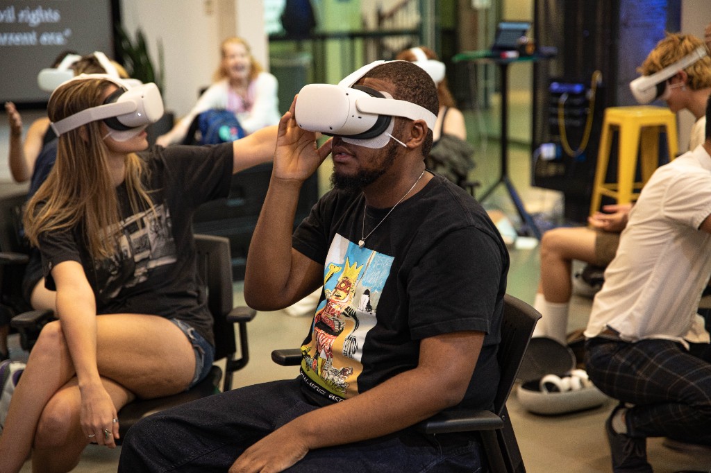 Participant in a VR headset with civil rights content visible on a nearby screen